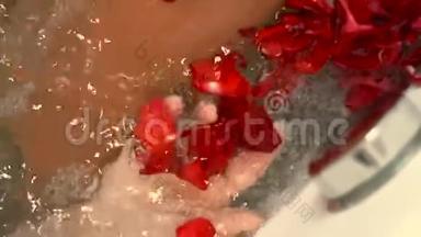 浪漫浴室水中的玫瑰花瓣。 带玫瑰花瓣的按摩浴缸的女人。 爱情和浪漫的蜜月